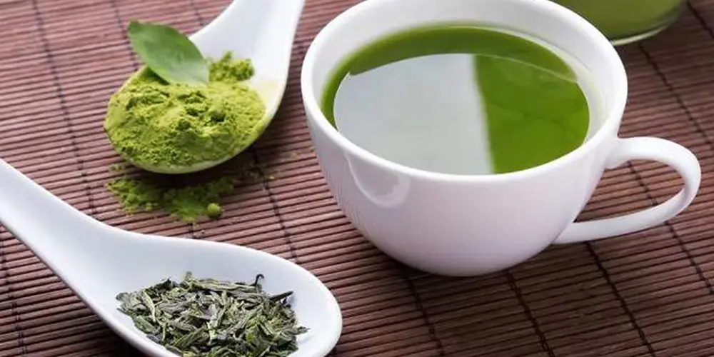 چای ماچا بدون کف در فنجان در کنار پودر ماچای آسیاب شده